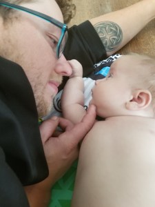 Timothy at a few months old laying on the floor beside his dad. He is feeling his dads face.