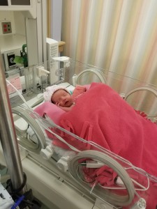 Photo of newborn Charlotte laying in a open incubator in the NICU.