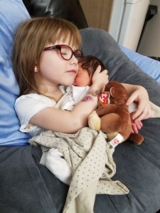 Photo of Hailey holding newborn Charlotte. Hailey is cuddling her.