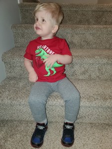 Photo of Timothy sitting on the stairs smiling with a red shirt that says heartbreaker